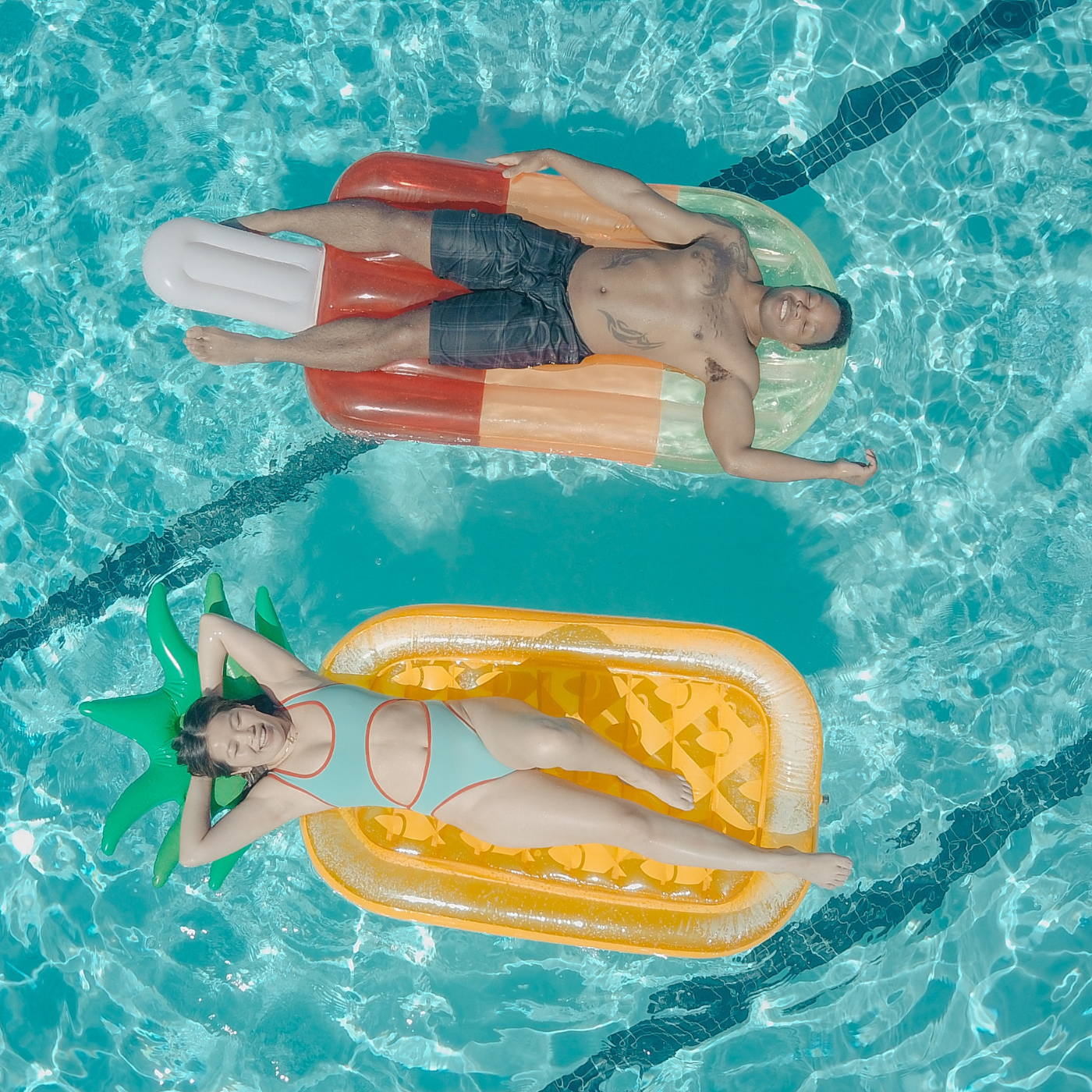 Mädchen und Mann liegen auf Luftmatratzen im Wasser