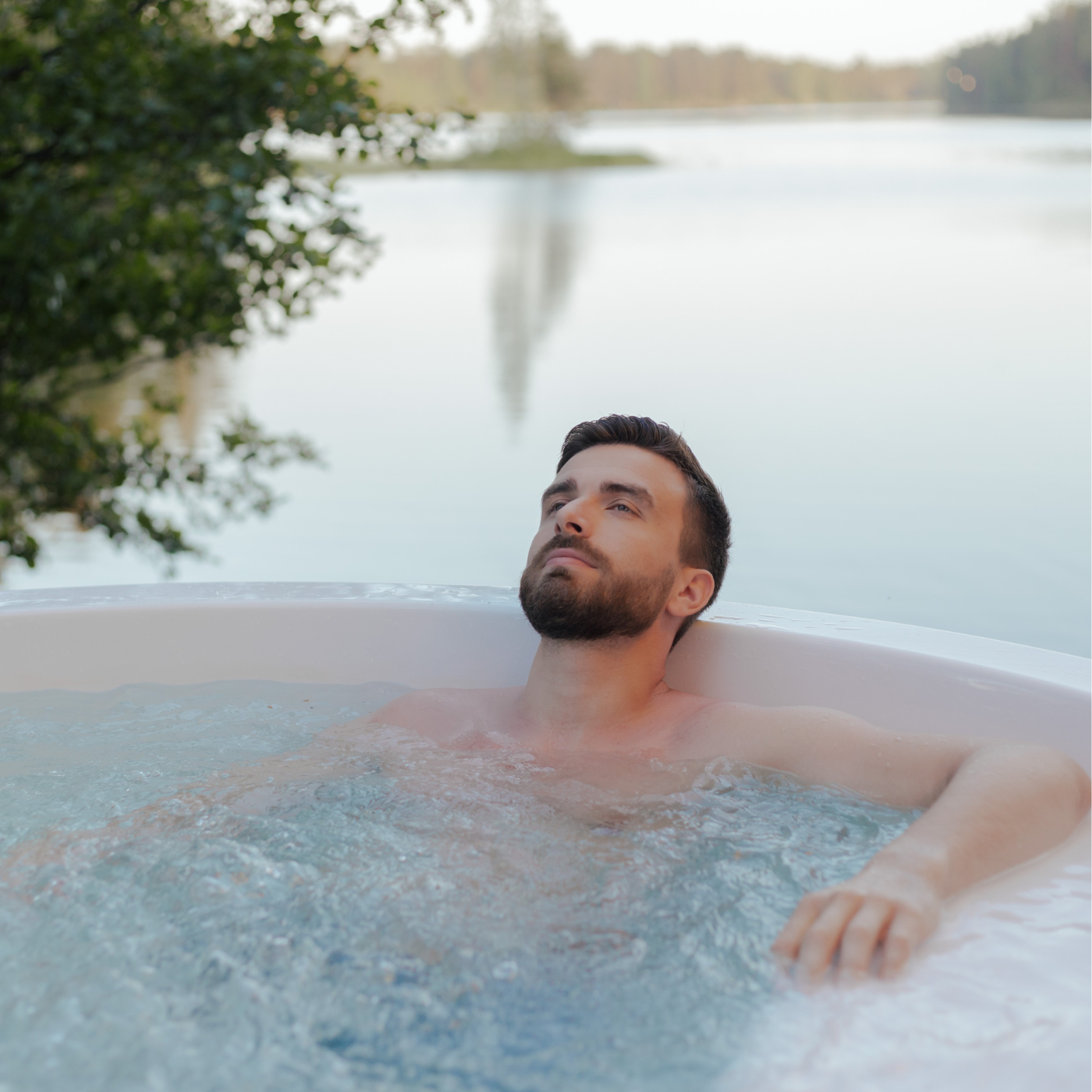 Mann entspannt im Whirlpool am See