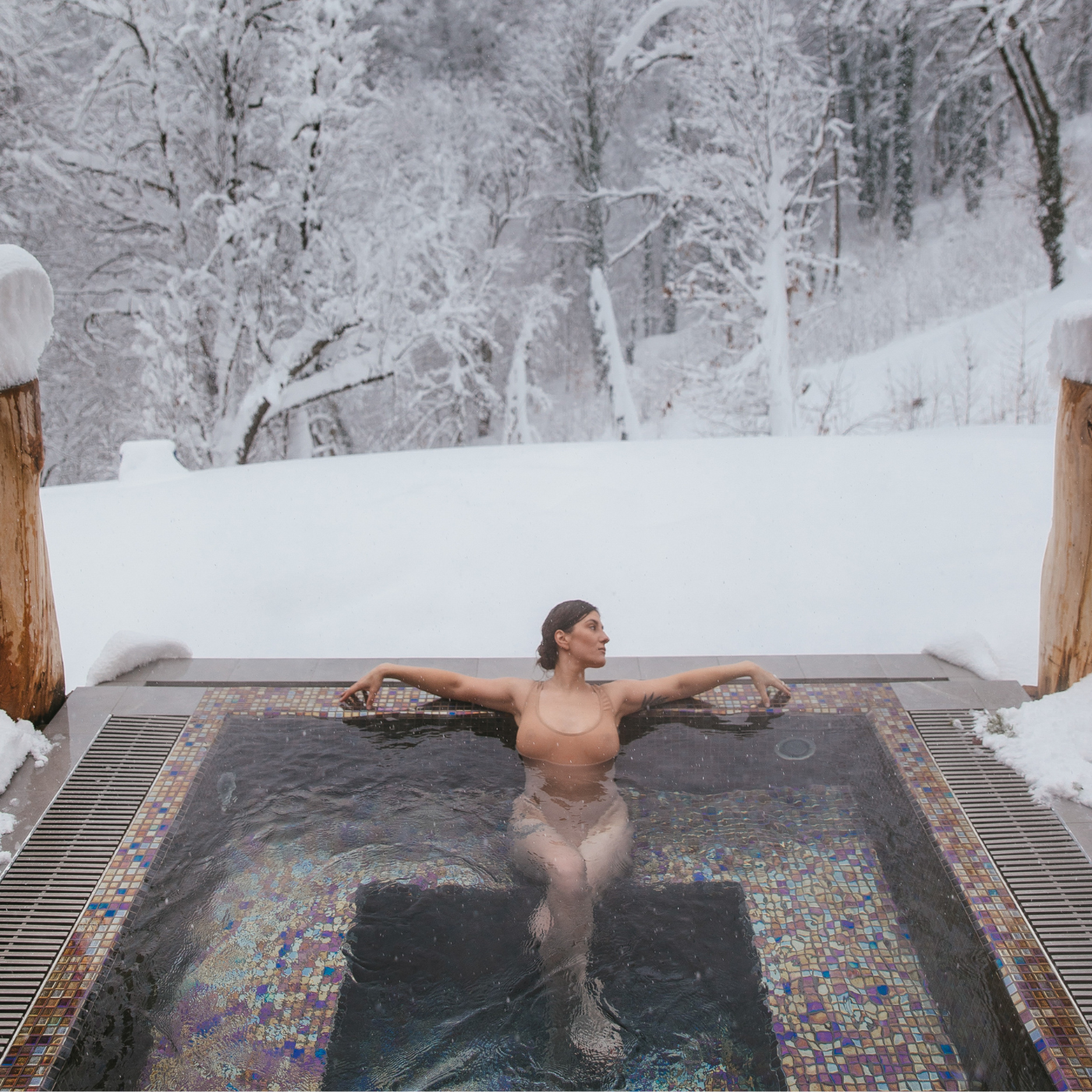 Frau sitzt in Whirlpool vor Winterlandschaft