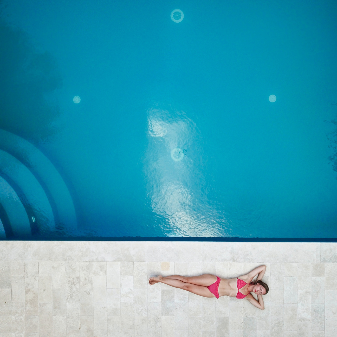 Frau liegt auf Boden neben Pool und entspannt sich
